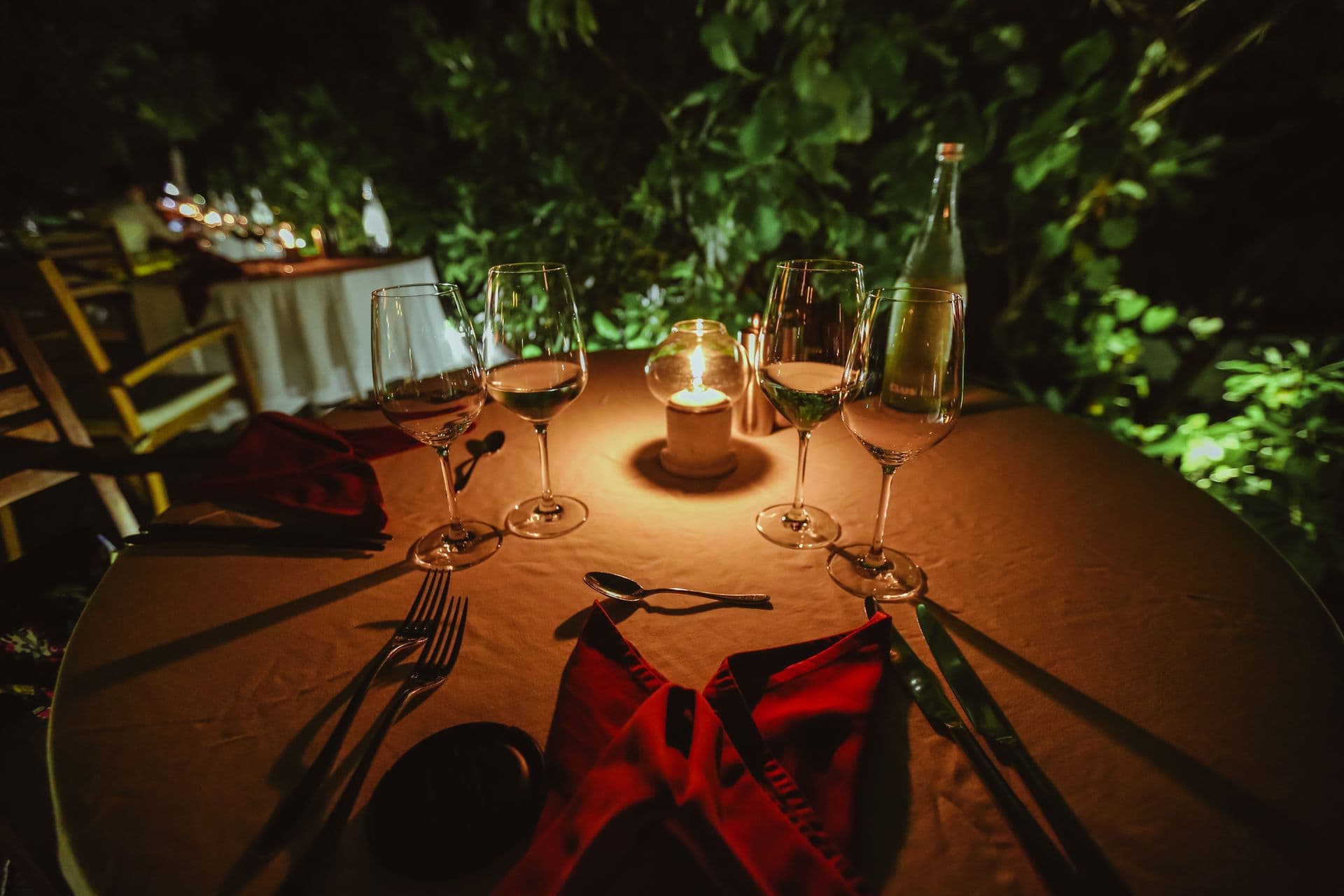 A candlelit table set for dinner beneath the trees