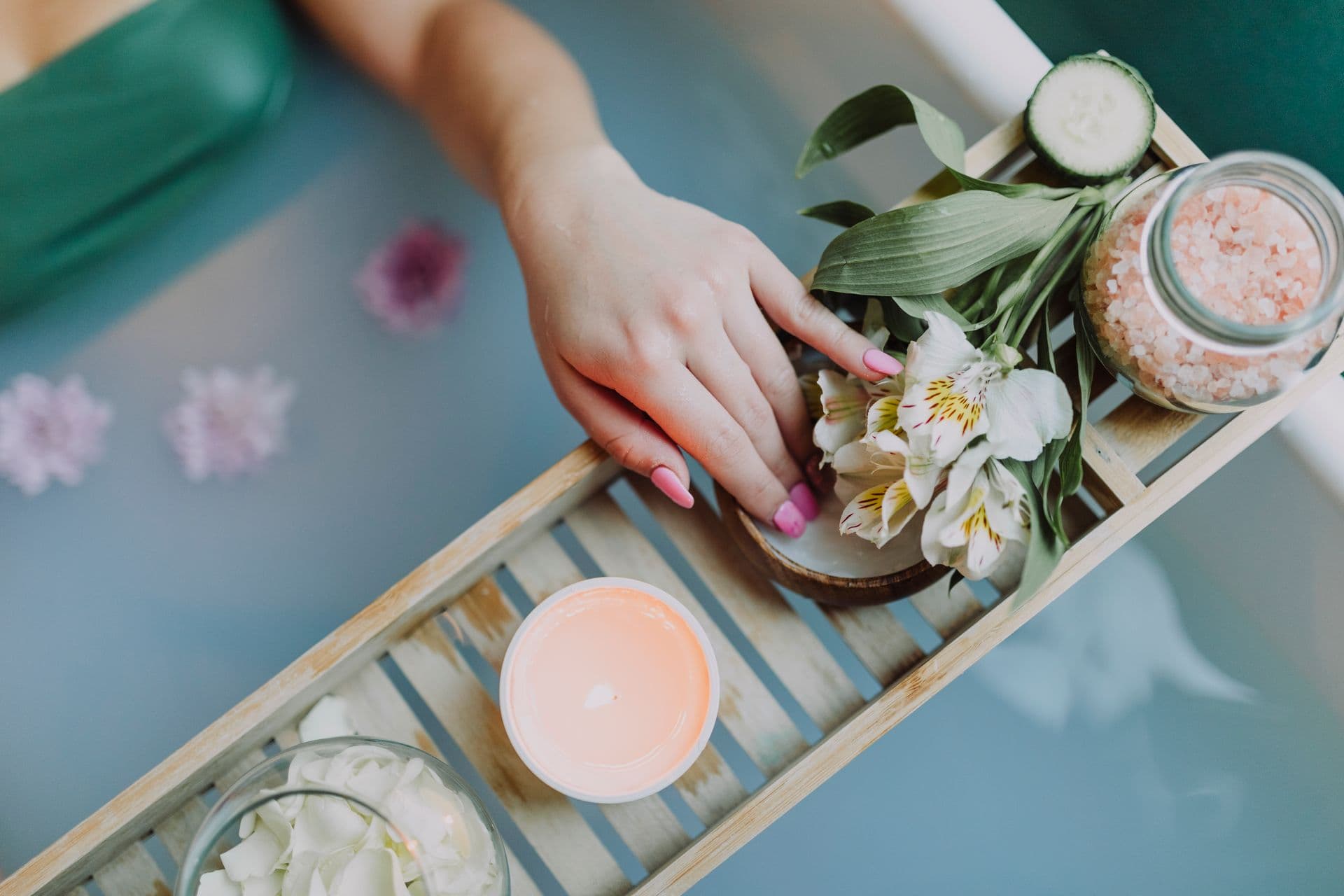 A spa treatment tray with flowers, salts, and candlelight